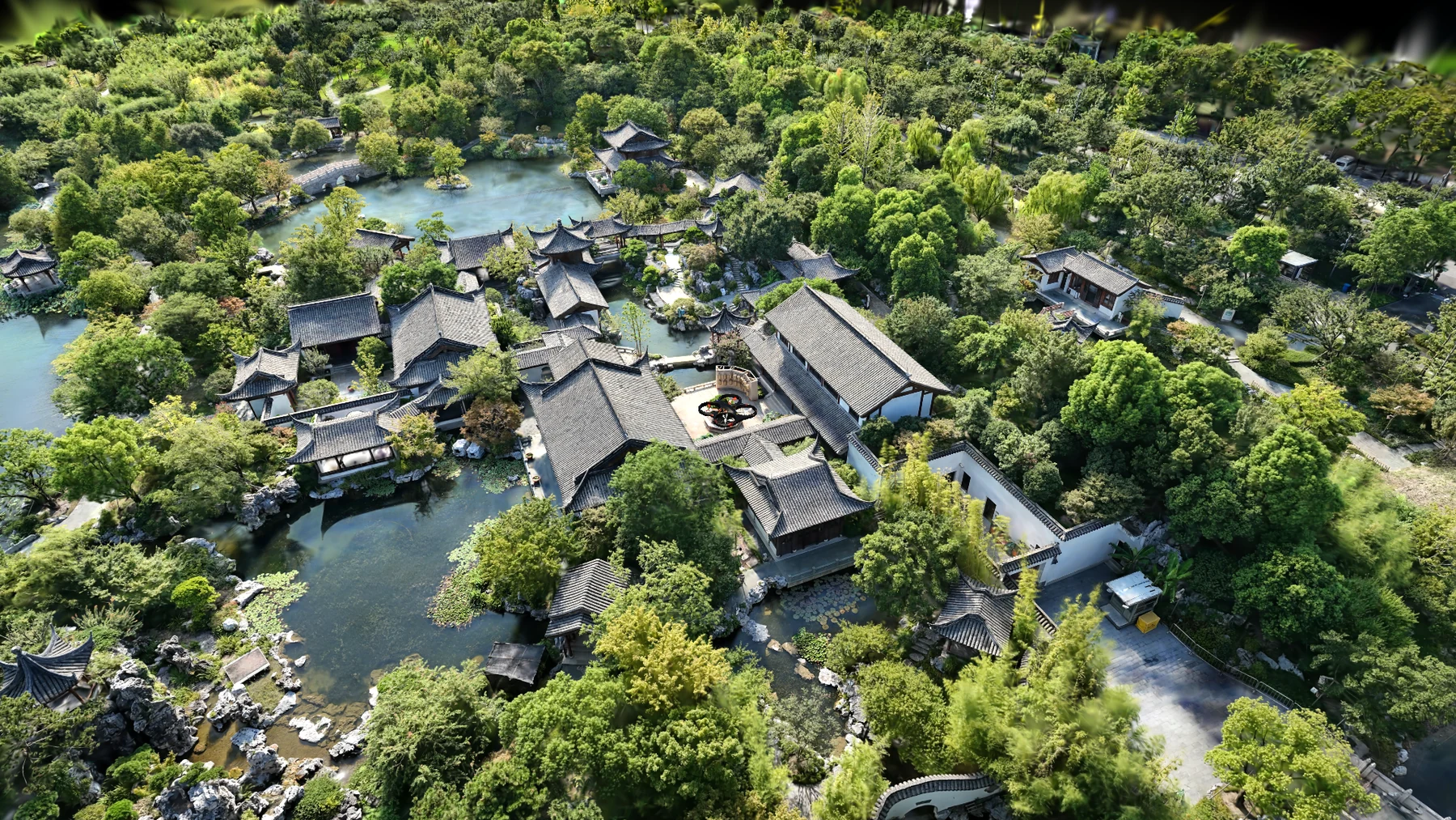 Expo East Gaussian reconstruction rendered in Unreal Engine, showing garden buildings, trees, and ponds from an oblique aerial view.